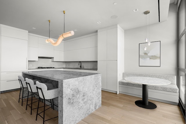 kitchen with modern cabinets, a breakfast bar, gas cooktop, a center island, and white cabinetry