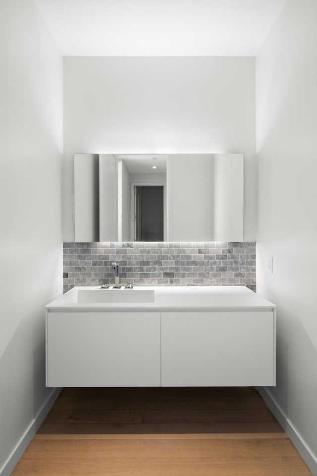 bathroom with decorative backsplash, baseboards, and wood finished floors