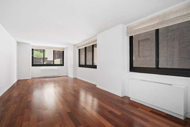 spare room featuring radiator, wood finished floors, and baseboards