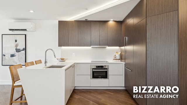 553 W 182nd St Unit 3R, New York City, NY 10033 - kitchen with stainless steel oven, an AC wall unit, a peninsula, light countertops, and modern cabinets