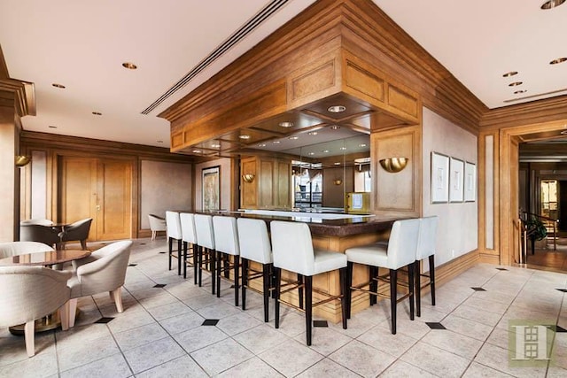 415 E 37th St Unit 31D, New York City, NY 10016 - kitchen with light tile patterned flooring, a kitchen bar, dark countertops, and ornamental molding