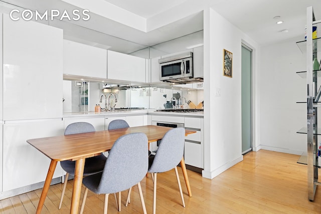 dining space featuring light wood finished floors, baseboards, and recessed lighting
