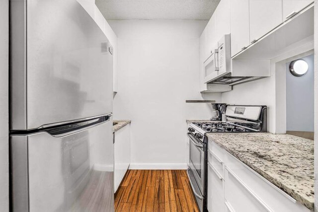 280 Rector Pl Unit 1I, New York City, NY 10280 - kitchen with stainless steel appliances, dark wood finished floors, white cabinets, and light stone countertops
