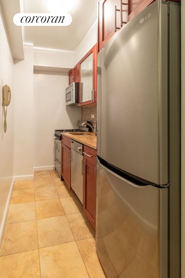 11 Riverside Dr Unit 4Kw, New York City, NY 10023 - kitchen featuring appliances with stainless steel finishes, decorative backsplash, baseboards, glass insert cabinets, and light tile patterned floors