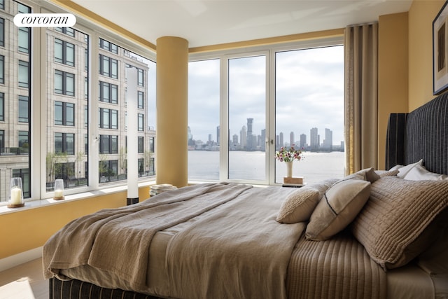 bedroom with a view of skyline, multiple windows, access to exterior, and a water view