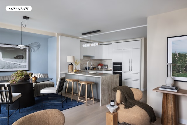 kitchen with modern cabinets, radiator heating unit, a peninsula, decorative backsplash, and light wood-style flooring
