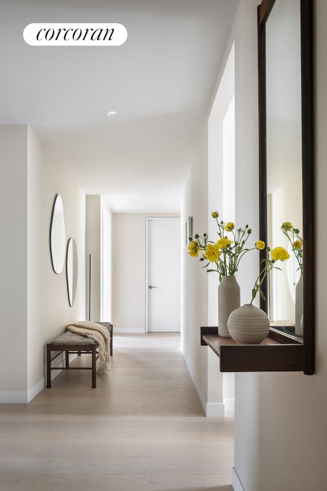 hall featuring light wood-type flooring and baseboards