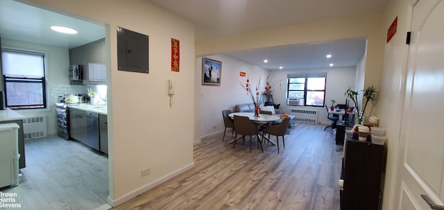 kitchen with electric panel, light wood-type flooring, radiator, stainless steel microwave, and recessed lighting