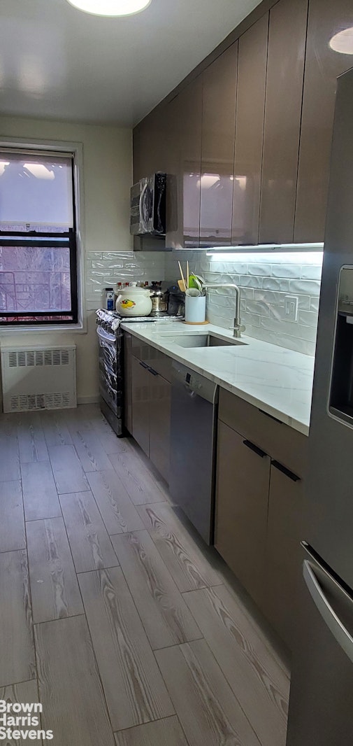 kitchen featuring radiator heating unit, appliances with stainless steel finishes, backsplash, and modern cabinets