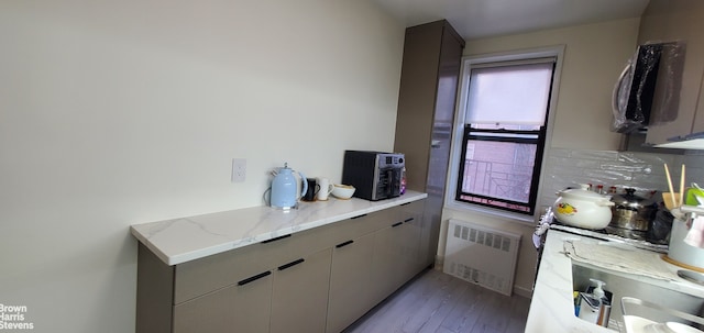 87-09 34th Ave Unit 3C, New York City, NY 11372 - kitchen featuring radiator, wood finished floors, gray cabinetry, light stone counters, and tasteful backsplash
