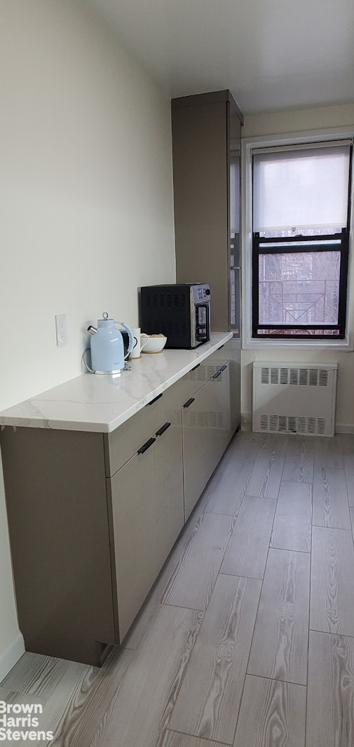 kitchen with radiator, light wood-style flooring, light stone countertops, and modern cabinets