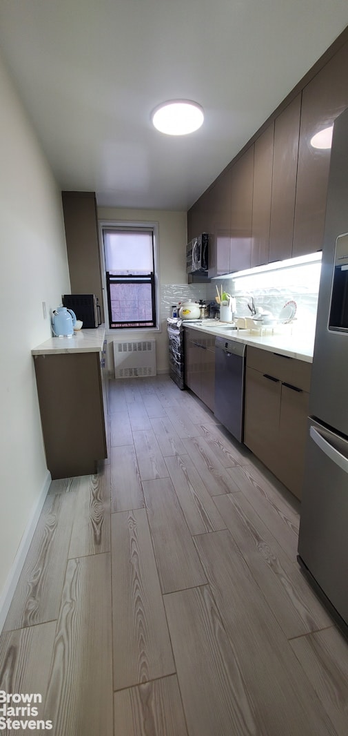 kitchen with light wood-style floors, light countertops, stainless steel appliances, and modern cabinets