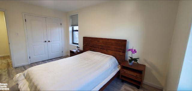 bedroom featuring a closet, wood finished floors, and baseboards