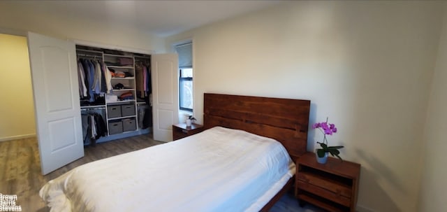 bedroom with wood finished floors, a closet, and baseboards