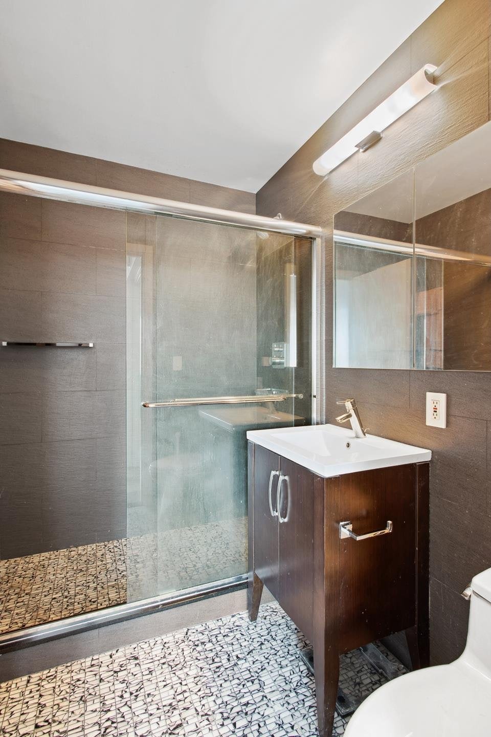 full bathroom with a shower stall, vanity, toilet, and tile walls