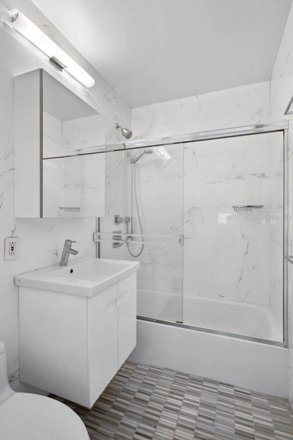 bathroom featuring toilet, combined bath / shower with glass door, and vanity
