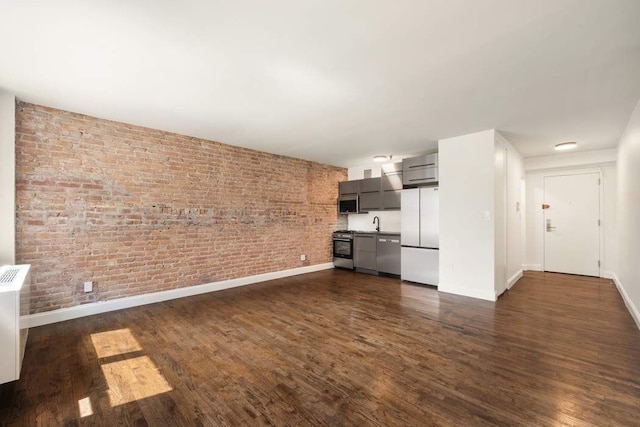unfurnished living room featuring baseboards, dark wood-style flooring, and a sink