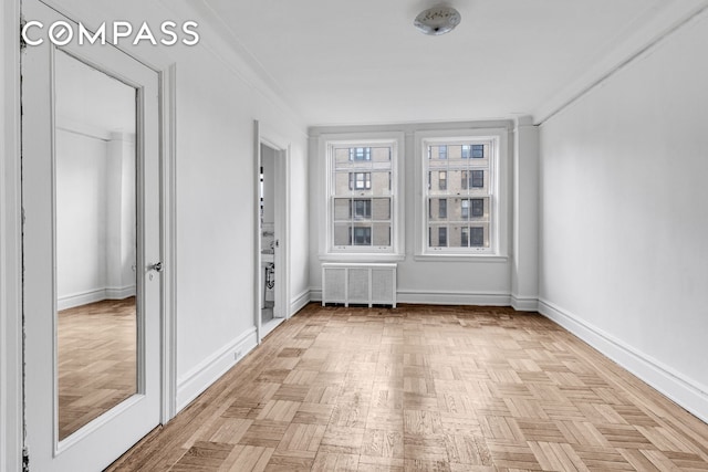 spare room with radiator, baseboards, and ornamental molding