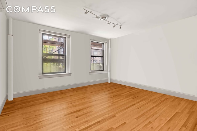 spare room with light wood-type flooring, track lighting, and healthy amount of natural light