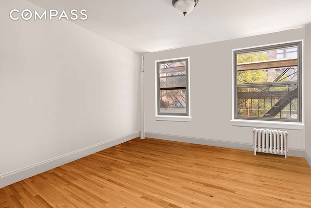 unfurnished room featuring radiator heating unit, plenty of natural light, and light wood-style flooring