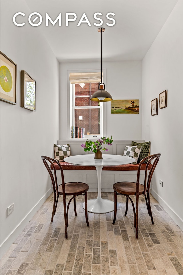 dining space with breakfast area, baseboards, and brick patterned floors