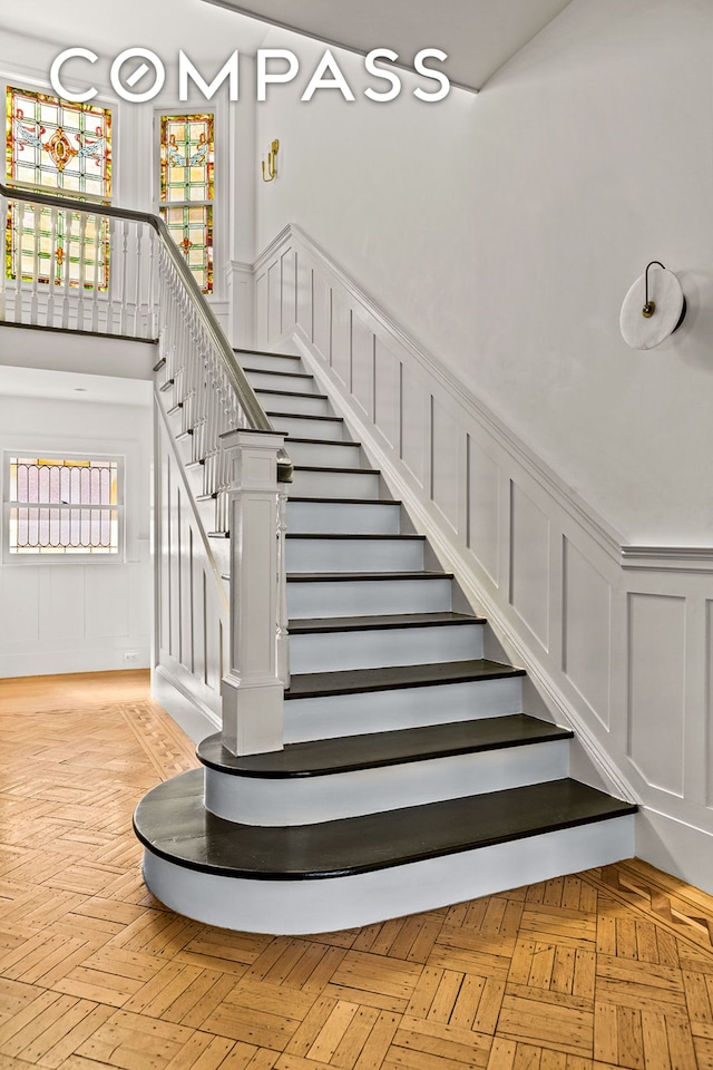 staircase with a decorative wall and wainscoting