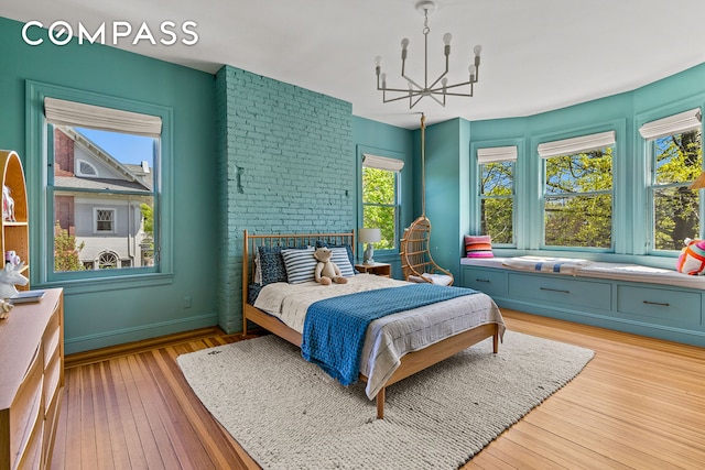 bedroom with a chandelier, light wood-type flooring, and baseboards