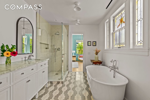 full bath with a shower stall, vanity, and a soaking tub