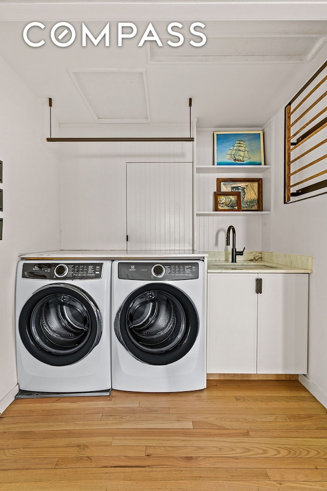 laundry area with washing machine and dryer, cabinet space, and light wood finished floors