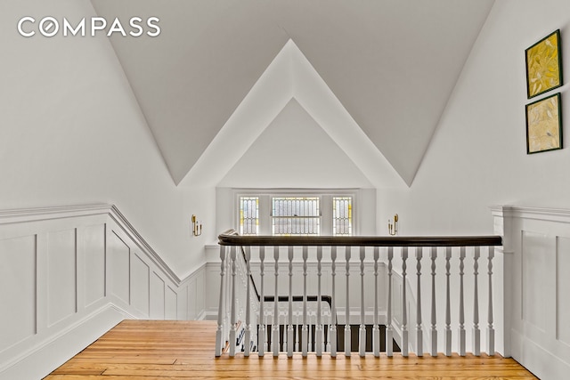 stairway featuring wainscoting, a decorative wall, and wood finished floors
