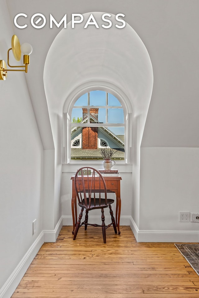 sitting room featuring light wood-style flooring, baseboards, and lofted ceiling