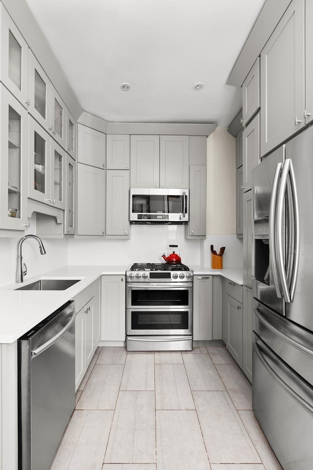 80 Winthrop St Unit 4C, New York City, NY 11225 - kitchen featuring stainless steel appliances, a sink, gray cabinets, light countertops, and glass insert cabinets