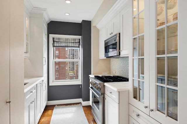 123 E 37th St Unit 11C, New York City, NY 10016 - kitchen with appliances with stainless steel finishes, white cabinetry, baseboards, backsplash, and glass insert cabinets