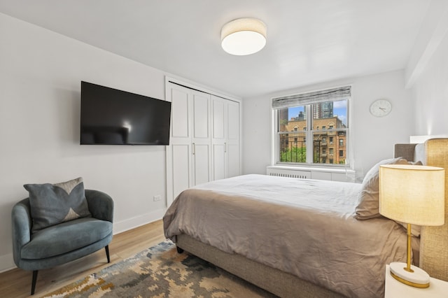 bedroom featuring wood finished floors, baseboards, and a closet