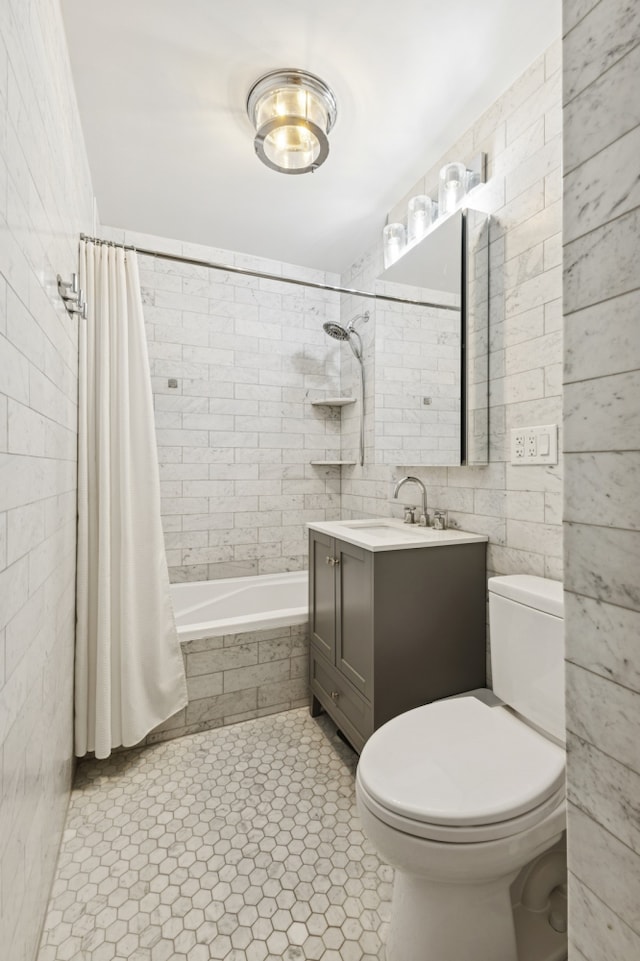 full bath with tile walls, toilet, vanity, tiled shower / bath combo, and tile patterned flooring