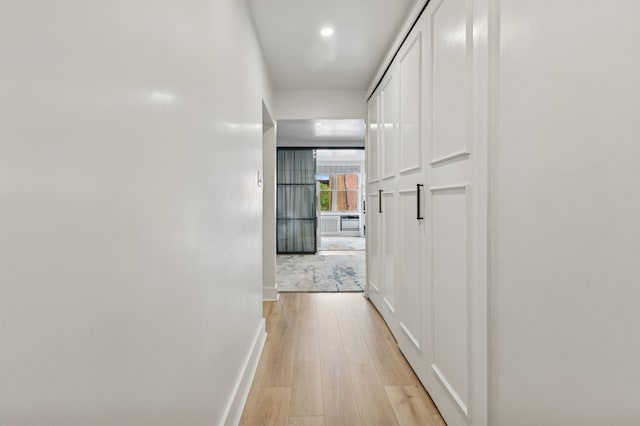 hall featuring light wood-type flooring, baseboards, and recessed lighting