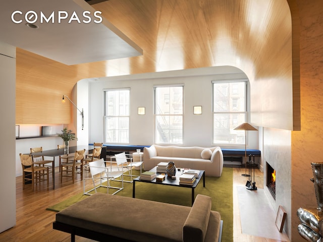 living room featuring arched walkways, wood finished floors, and a high end fireplace