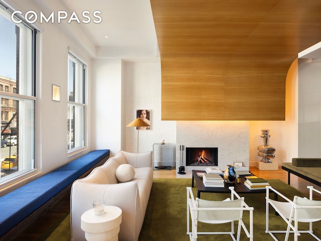 living area featuring plenty of natural light, a lit fireplace, and arched walkways