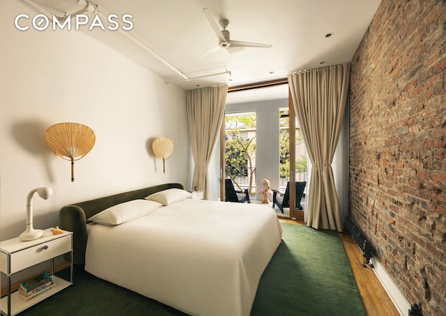 bedroom with wood finished floors, brick wall, and access to exterior