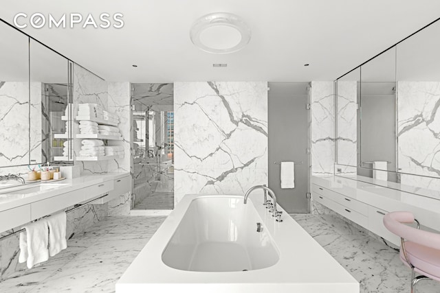 27 Wooster St Ph, Ph, New York City, NY 10013 - full bathroom featuring a soaking tub, a marble finish shower, vanity, tile walls, and stone wall
