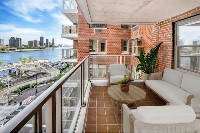 balcony with a water view, a view of skyline, and outdoor lounge area