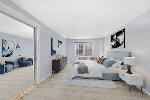 bedroom featuring wood finished floors, radiator, and baseboards