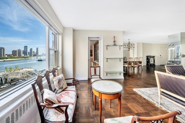 living area featuring a chandelier, a water view, baseboards, and a skyline view