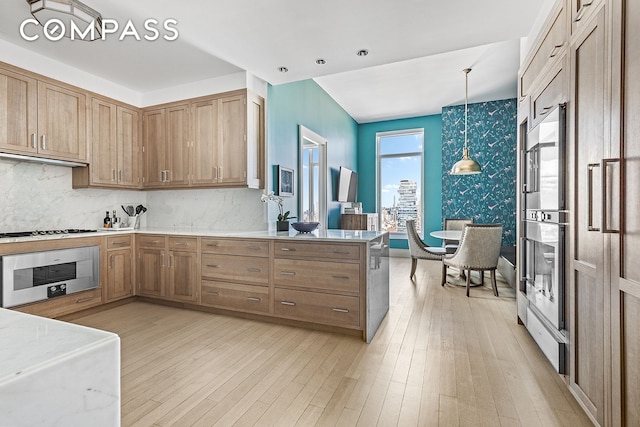30 Park Pl Unit 64A, New York City, NY 10007 - kitchen featuring light wood-style flooring, a peninsula, decorative light fixtures, appliances with stainless steel finishes, and decorative backsplash