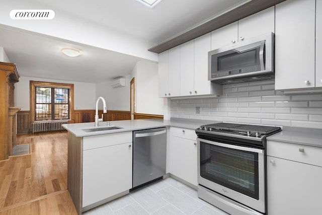 425 Convent Ave, New York City, NY 10031 - kitchen with appliances with stainless steel finishes, a peninsula, a sink, white cabinetry, and light countertops