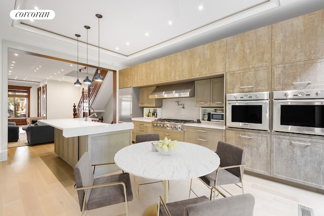 425 Convent Ave, New York City, NY 10031 - kitchen featuring appliances with stainless steel finishes, wall chimney range hood, light wood finished floors, light countertops, and recessed lighting