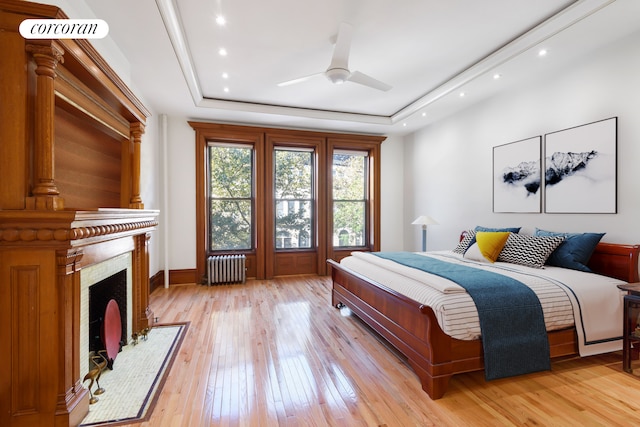 425 Convent Ave, New York City, NY 10031 - bedroom featuring radiator, a raised ceiling, light wood-style floors, baseboards, and a premium fireplace