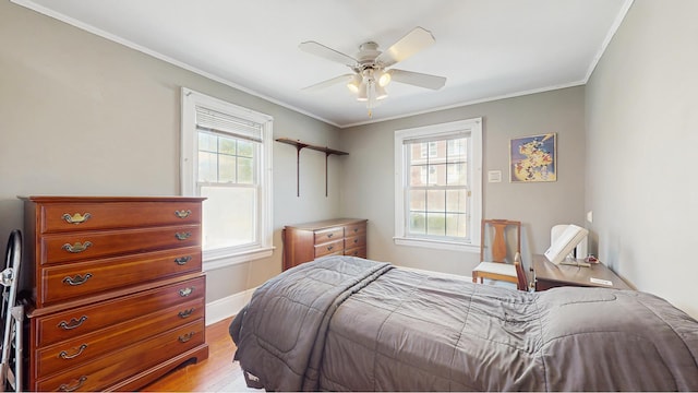 bedroom with light wood-type flooring, ornamental molding, baseboards, and ceiling fan