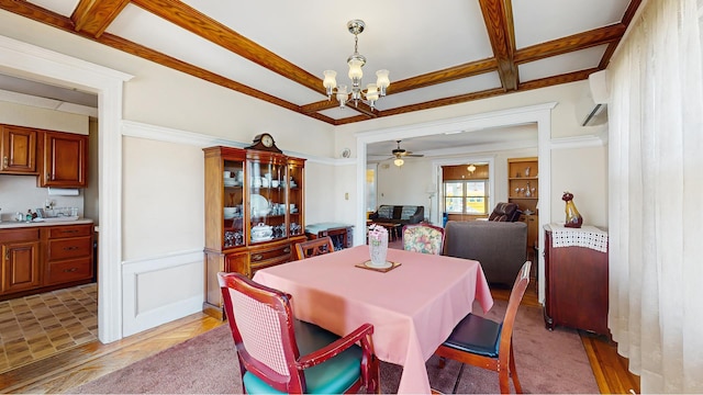 dining room with a chandelier, ceiling fan, an AC wall unit, light wood-style flooring, and a wainscoted wall