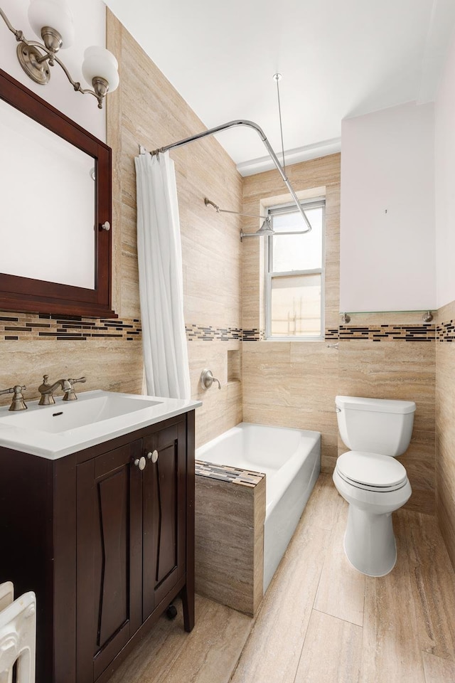 full bath with tile walls, tiled shower / bath combo, toilet, vanity, and decorative backsplash